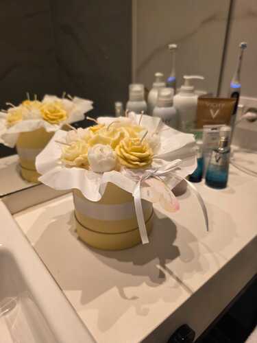 Box de flores de soja reflejado en el espejo de vanitory de bano junto a productos de belleza.